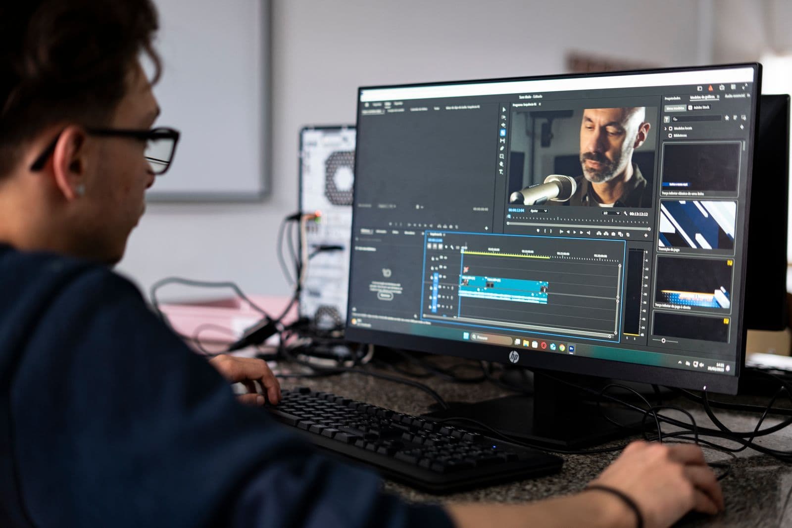 Video editor working at a computer while uploading a large project over NBN.